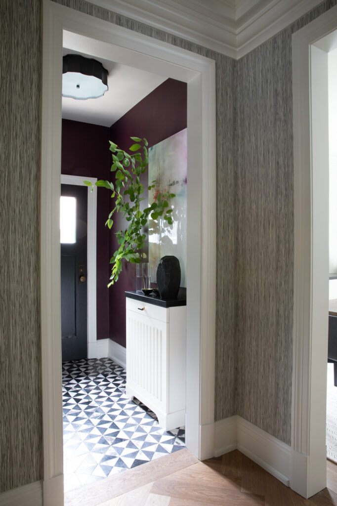 Functional entrance foyer with patterned tile floor, storage cabinet and deep-toned walls by Gillian Gillies Interiors